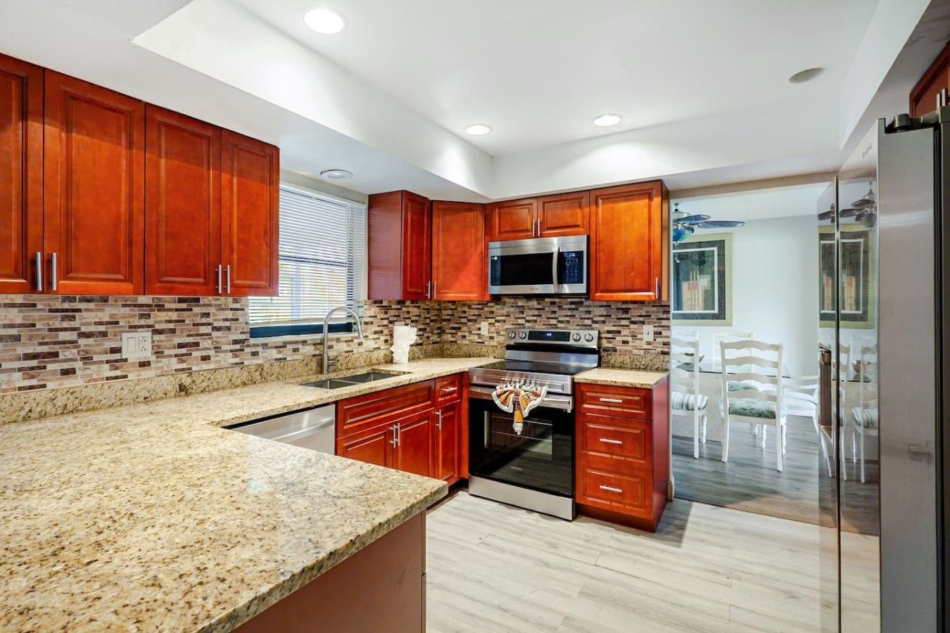 A modern kitchen with granite countertops, stainless steel appliances, and wooden cabinetry.