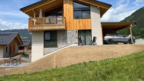 A modern two-story house with a balcony, a stone facade, and a car parked in the driveway. - Holiday Home on the ski Slope With Sauna (Sankt Lambrecht)