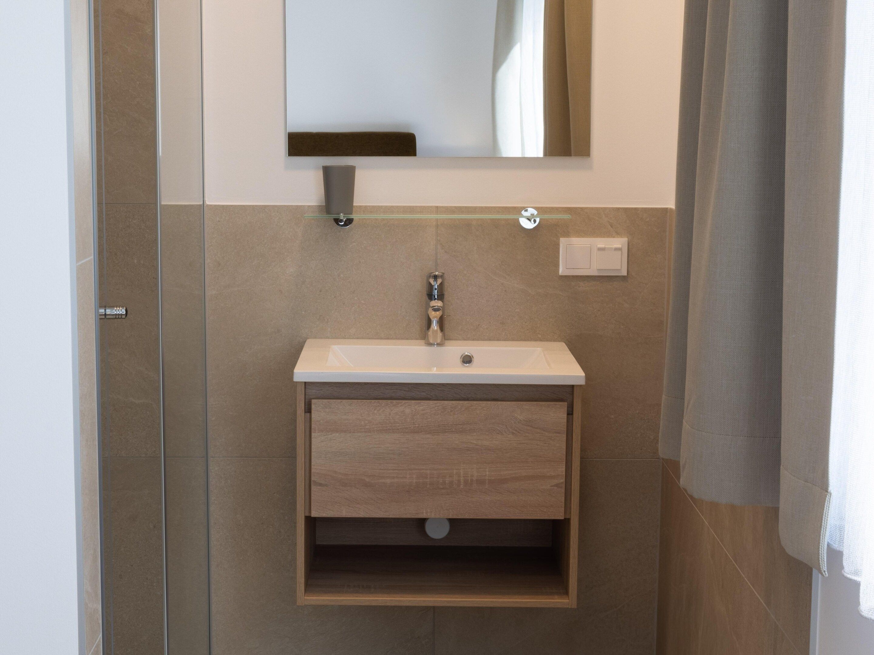 A bathroom with a built-in sink, a mirror above it, and a towel hanging on the wall.
