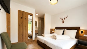 A bedroom with a bed, a chair, a wooden door, a mirror, and a wall-mounted deer head decoration. - Holiday Home on the ski Slope With Sauna (Sankt Lambrecht)