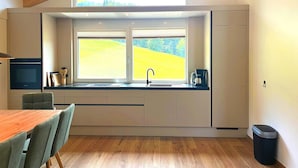 A modern kitchen with a large window, a sink, and a dining area with chairs. - Holiday Home on the ski Slope With Sauna (Sankt Lambrecht)