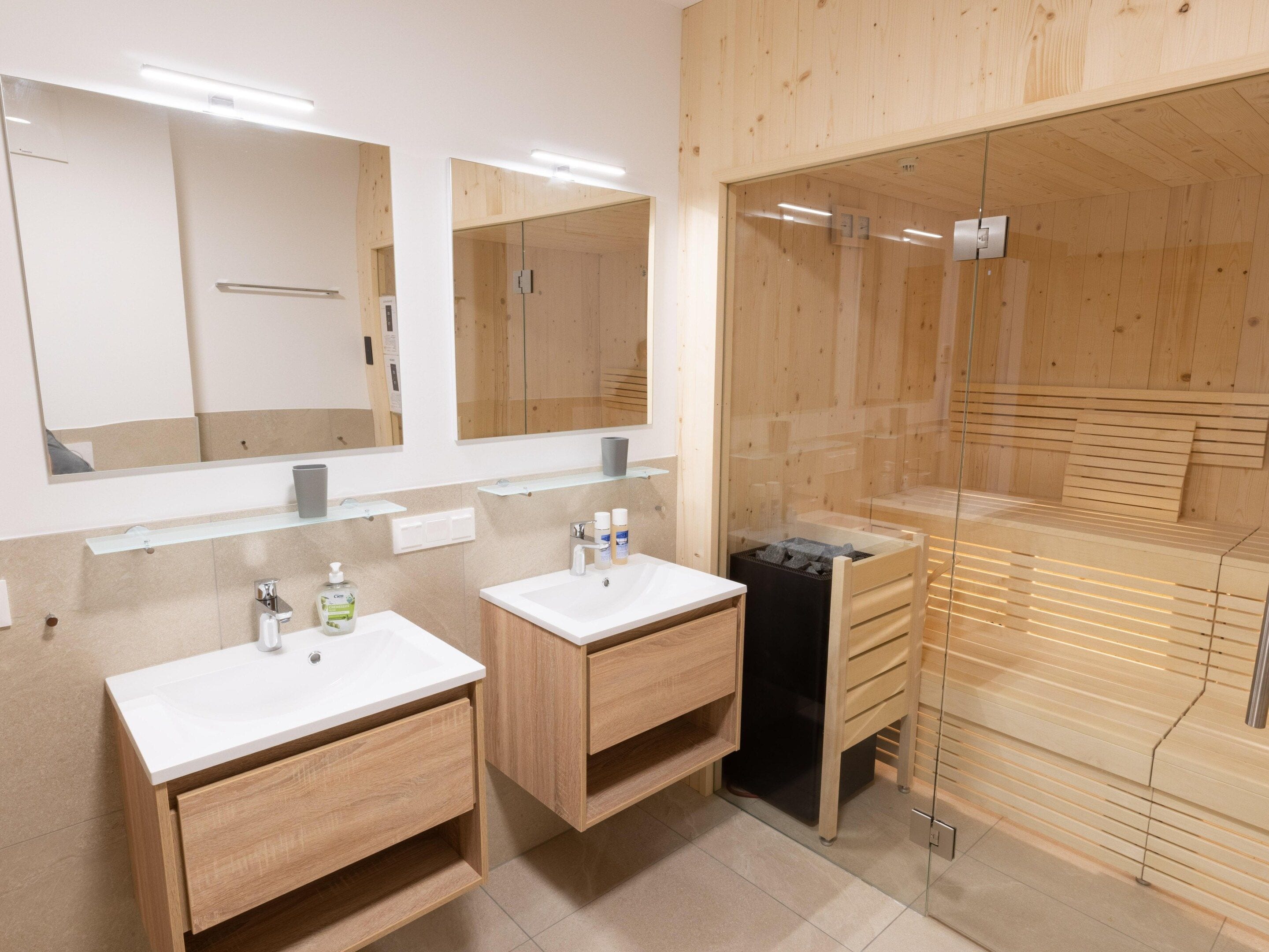 A modern bathroom with two sinks, a mirror, and a glass shower enclosure.