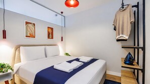 A modern hotel room with a bed, a hanging clothing rack, and artwork on the wall. - Magical 2 Bedroom Apartment At Monnas Suite (Istanbul)
