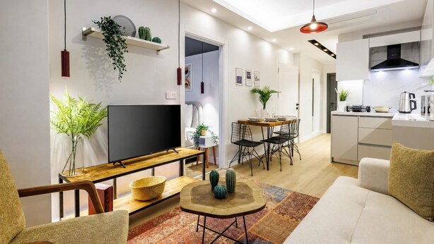 A modern living room with a flat-screen TV, a dining area with a table and chairs, a kitchen with a stove and microwave, and a staircase leading to another level. - Magical 2 Bedroom Apartment At Monnas Suite (Istanbul)
