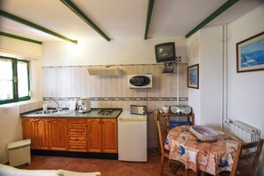 A compact kitchen with wooden cabinets, a refrigerator, a microwave, a toaster, and a small television. - Casa Victor - Apartment 4 (La Orotava)