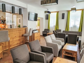 Eine moderne Hotellobby mit einem hölzernen Empfangstresen, grau gepolsterten Sitzgelegenheiten und einem an der Wand befestigten Flachbildfernseher.