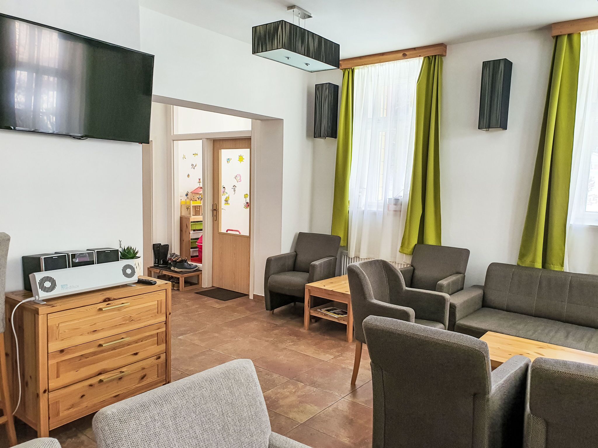 A living room with a flat-screen TV, grey sofas, a wooden cabinet, and a small table.