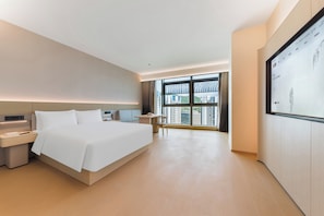 A modern hotel room with a large bed, bedside tables, a desk, and a large window offering a city view.