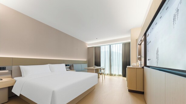 A modern hotel room with a large bed, bedside tables, a desk, and a wardrobe. - JI Hotel Shenzhen Xiaomeisha (Shenzhen)