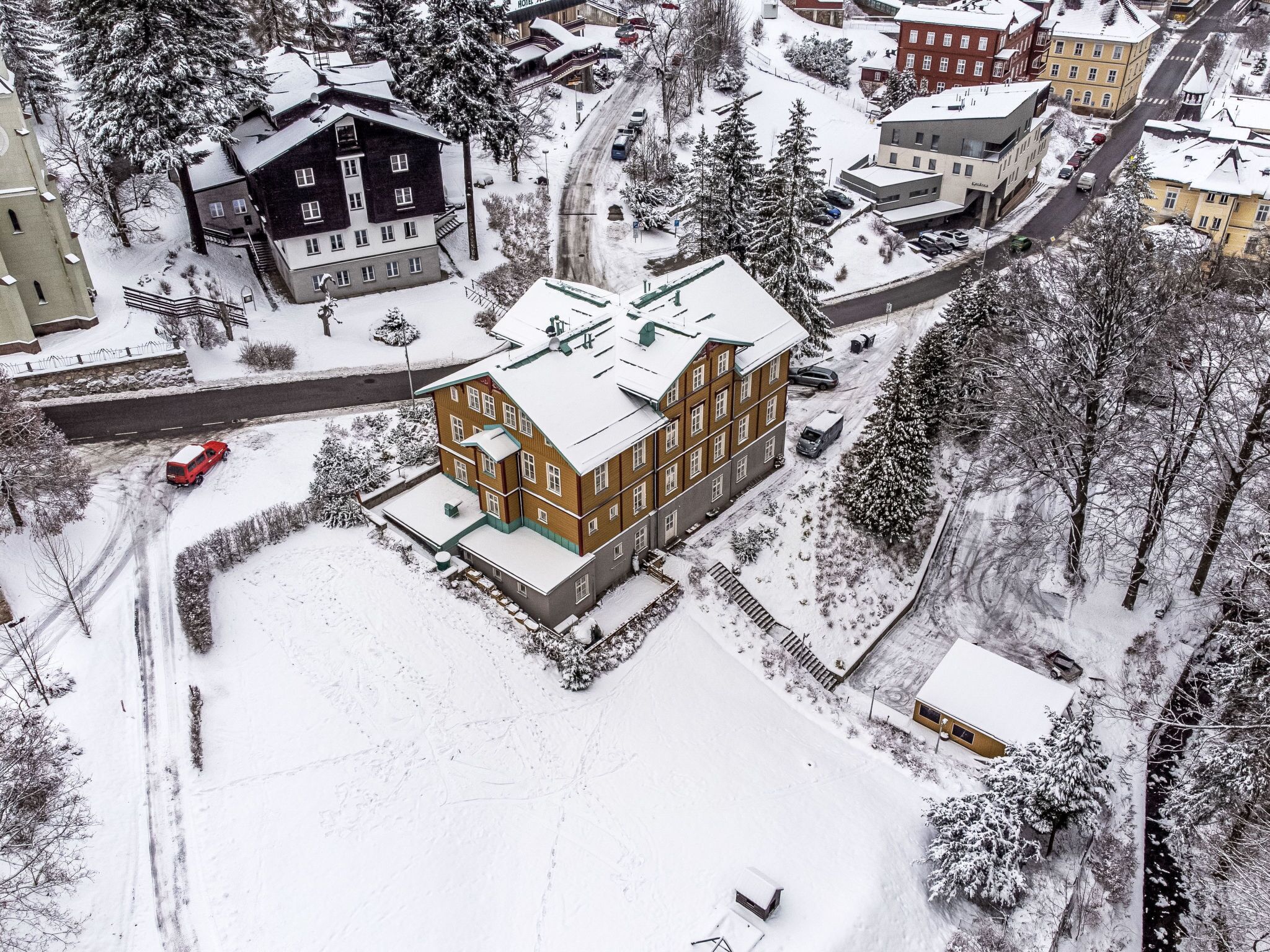 Un edificio de varios pisos con tejado nevado y zona de estacionamiento contigua.