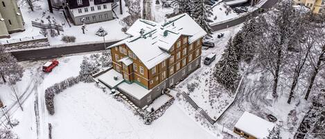 Un edificio de varios pisos con tejado nevado y zona de estacionamiento contigua.
