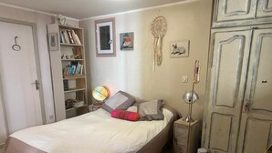 Et soveværelse med seng, sengetøj, lampe, bogreol og garderobeskab.