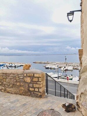 A stone wall with a cat, a stop sign, and boats in the background. - Lovely 2-bedroom house with AC in quaint Mèze (Mèze)