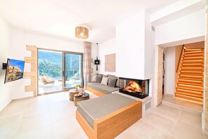 Ein modernes Wohnzimmer mit Kamin, einer Couch und einem Essbereich.