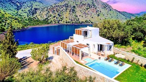 A modern villa with a pool, surrounded by lush greenery and mountains. - Blue Lake Villa Heated Pool (Kavallos)