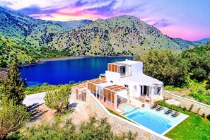 Eine moderne Villa mit Pool, umgeben von üppiger Vegetation und Bergen.