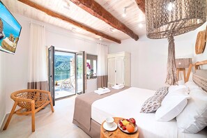 Ein Hotelzimmer mit einem Bett, einem Korbstuhl, einer Obstschale und Blick ins Freie.