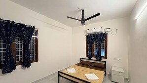 Camera da letto con un letto, una ventola a soffitto, un condizionatore d'aria e una finestra con tende.