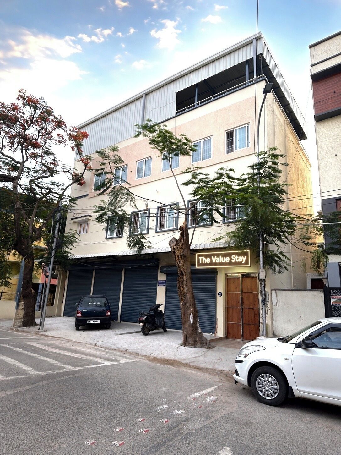 A building with a sign reading 'The Value Stay,' a closed car, and a parked motorcycle.