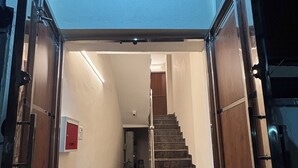 Un corridoio che porta a una scala, con un rilevatore di fumo sul muro.