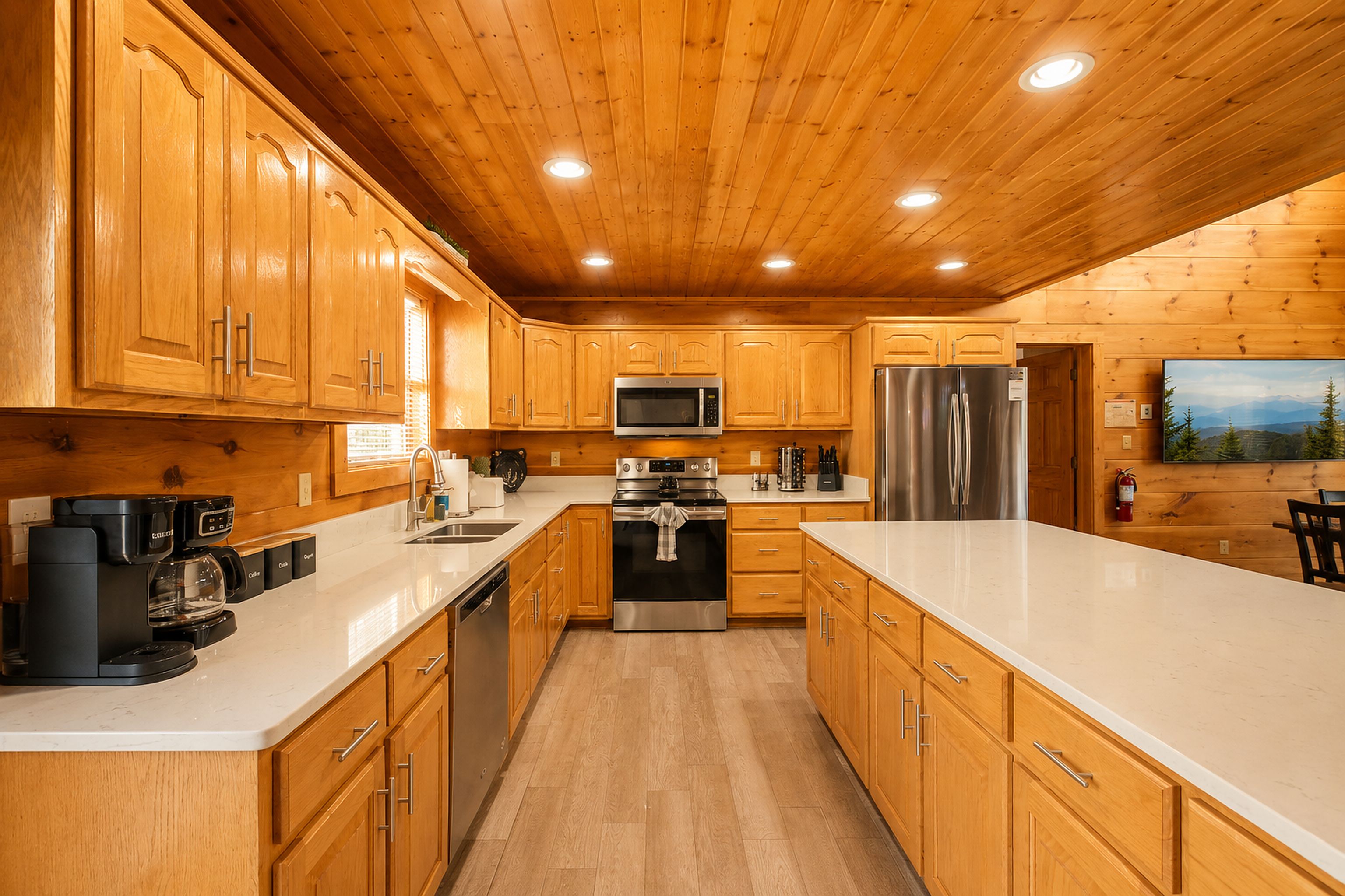 Una cocina moderna con gabinetes de madera, electrodomésticos de acero inoxidable y encimera blanca.