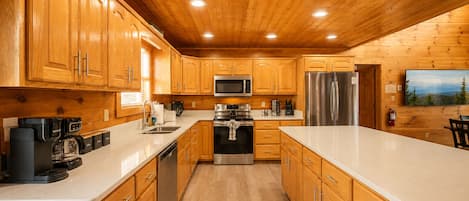Una cocina moderna con gabinetes de madera, electrodomésticos de acero inoxidable y encimera blanca.