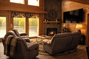 A cozy living room with a fireplace, comfortable seating, and a television. - Hot Tub, Pool Table & Arcade I Ridgetop View Cabin (Sevierville)