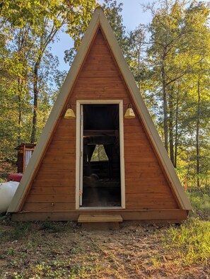A wooden cabin with a triangular roof, a door, and a bench outside. - Tranquil Glamping Cabin in Athens (Athens)