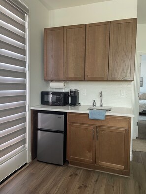 A compact kitchen with wooden cabinets, a stainless steel refrigerator, a microwave, a coffee maker, and a sink. - Cute Boho Guest Suite | Private Entry | Great Location (Roseville)