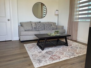 A living room with a sofa, a coffee table, a mirror, and a floor lamp.