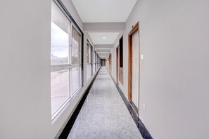 Un passadís amb grans finestres a un costat i portes a l'altre, que dona accés a habitacions.