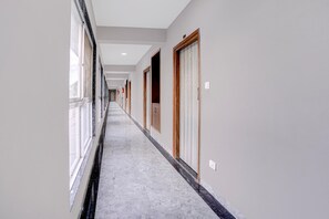 A long hallway with doors on both sides, a tiled floor, and a ceiling with recessed lighting.