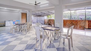 A spacious room with a high ceiling, ceiling fans, and a view of a brick wall and greenery outside. - Palette Virar Mumbai (Vasai)