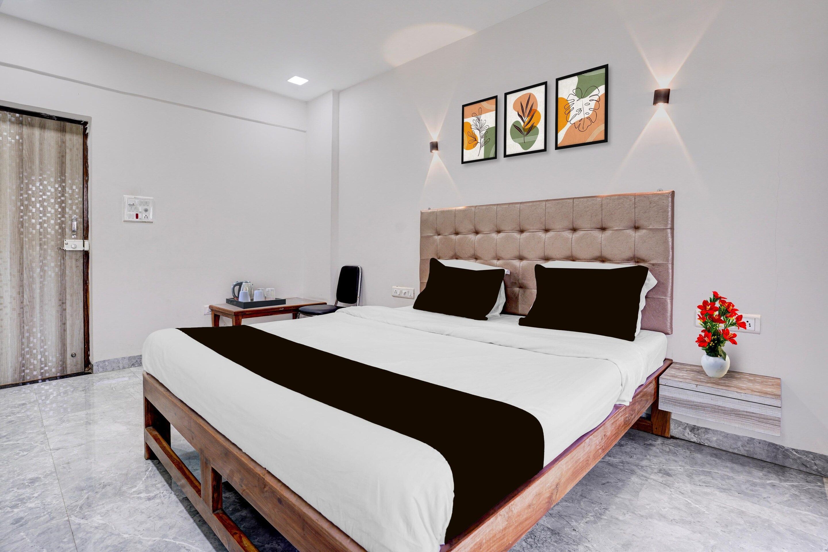 Una habitación de hotel con una cama grande, una mesita de noche, una lámpara de pared y un cuadro.