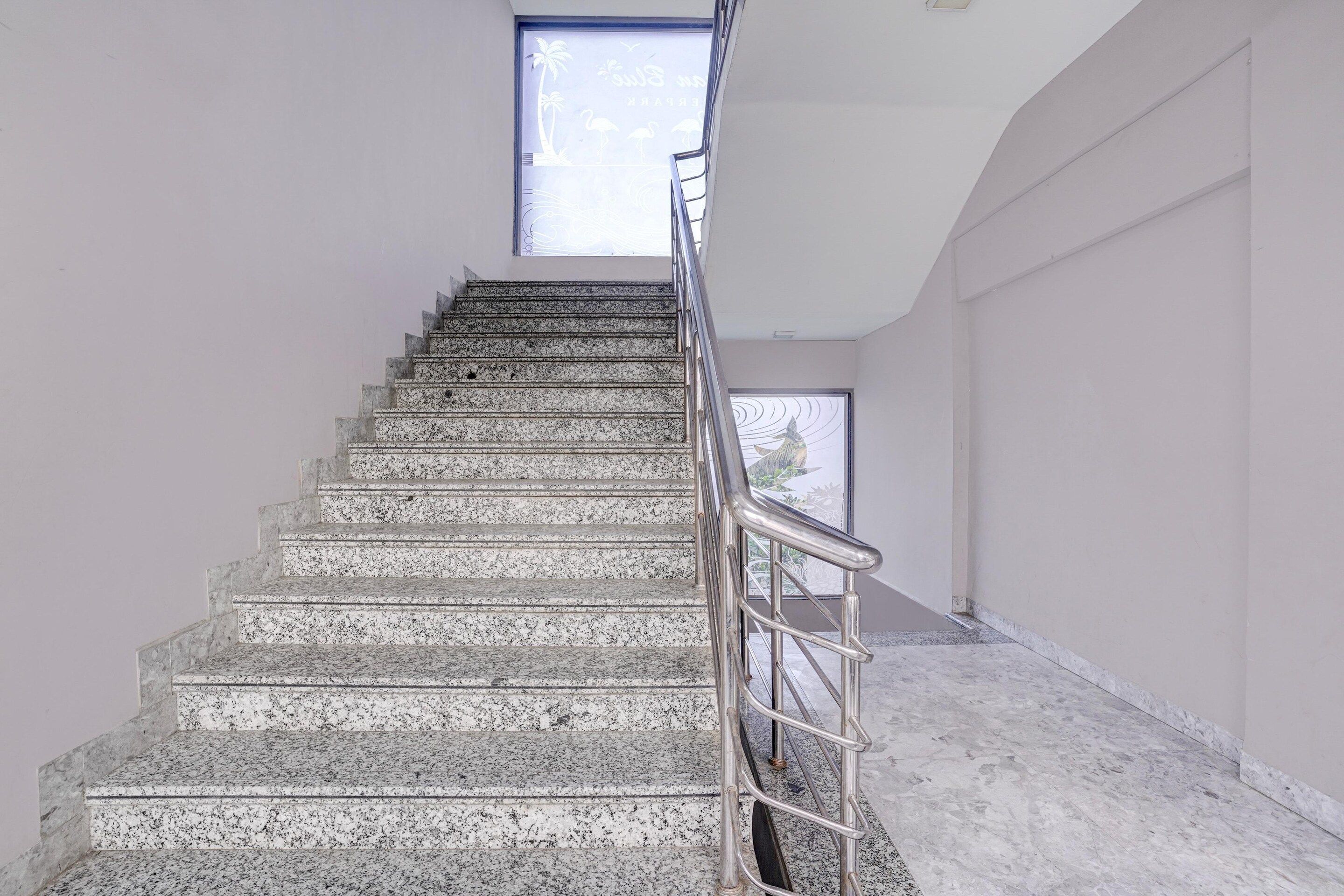Una escalera con barandilla metálica que lleva a una puerta con un ventanal encima.