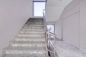 A staircase with a metal handrail leading to a door with a window above.