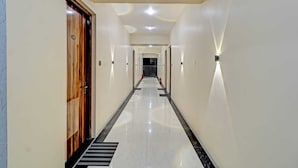 A hotel hallway with a wooden door, a black and white striped floor, and recessed lighting.