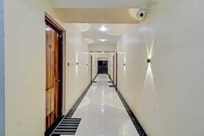 A hotel hallway with a wooden door, a black and white striped floor, and recessed lighting. - Palette Virar Mumbai (Vasai)
