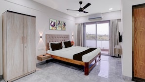 A modern bedroom with a large bed, a wardrobe, a ceiling fan, and a view through a large window. - Palette Virar Mumbai (Vasai)