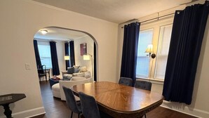 A dining area with a wooden table and chairs, a small table with a lamp, and a view of a living room through an archway. - San Marco Courtyard Retreat, a Peaceful 2-Bedroom Apartment in Jacksonville (Jacksonville)