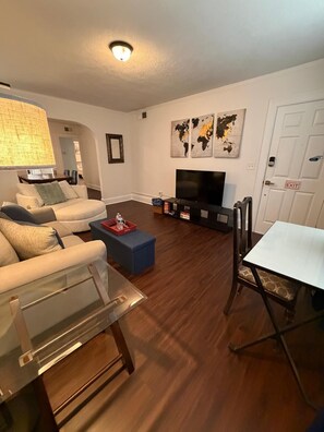 A living room with a sofa, coffee table, TV, and world map artwork.