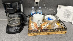 A coffee maker, two water bottles, a coffee mug, a basket with snacks, and a certificate on a countertop. - San Marco Courtyard Retreat, a Peaceful 2-Bedroom Apartment in Jacksonville (Jacksonville)