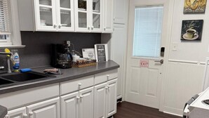 A kitchen with white cabinetry, a black countertop, and a dark wooden floor. - San Marco Courtyard Retreat, a Peaceful 2-Bedroom Apartment in Jacksonville (Jacksonville)