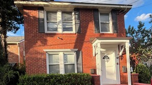 A two-story brick house with a front porch and a garage. - San Marco Courtyard Retreat, a Peaceful 2-Bedroom Apartment in Jacksonville (Jacksonville)