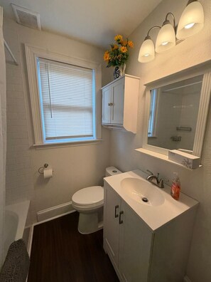 A bathroom with a toilet, sink, and window with blinds.
