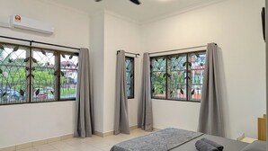 Une chambre à coucher avec un lit, un ventilateur de plafond, un appareil de climatisation et des fenêtres avec des rideaux.