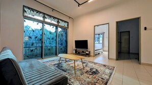 Un salon moderne avec un canapé, un téléviseur et un tapis à motifs.