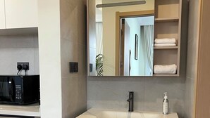 Une salle de bain moderne avec un grand miroir, un lavabo et un porte-serviettes.