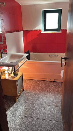 A bathroom with a bathtub, a sink, and a window. - Sleeps4-familyfriendly-balcony (Lagoa)