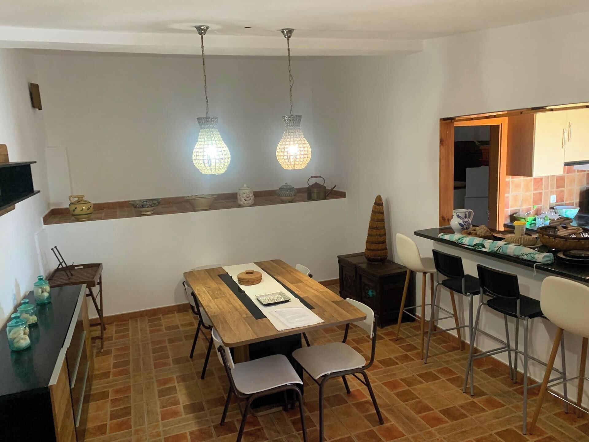 A dining area with a wooden table, chairs, and hanging pendant lights.
